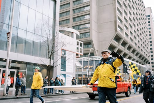 Participants in bright yellow jackets joyfully walk in a lively city parade