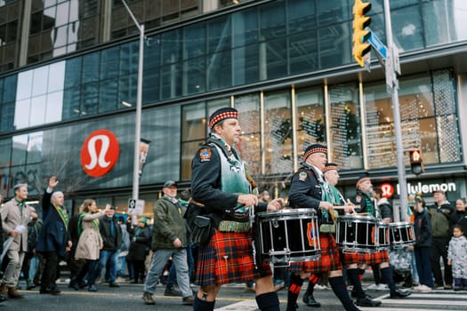 Drummers in kilts march in unison during a lively St Patricks Day parade