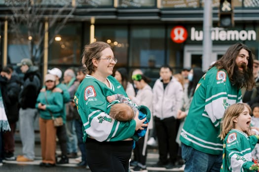 Families celebrate together at a bustling outdoor event in team jerseys.