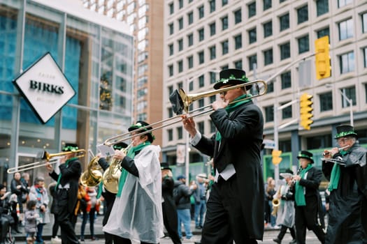 Musicians dressed in colorful costumes are marching in a lively city parade