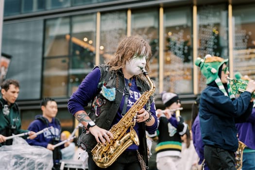 An energetic performer skillfully playing his saxophone at a lively street festival