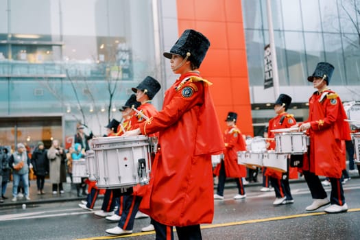 A lively and dynamic parade scene showcasing drummers dressed in vibrant rain gear