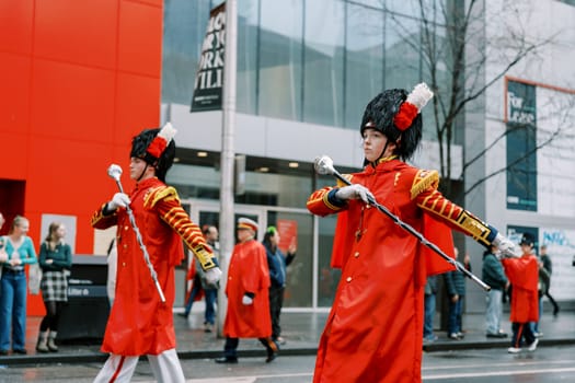 Lively performers in vibrant outfits march proudly through bustling city streets