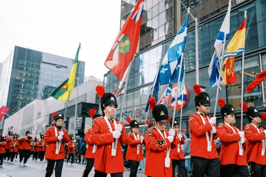A festive parade with uniformed marchers and colorful flags showing community diversity