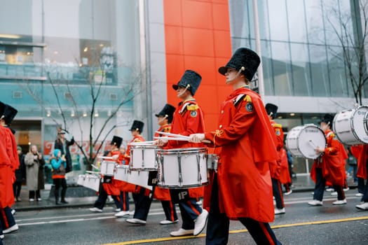 A vibrant and colorful marching band is performing energetically in the city street