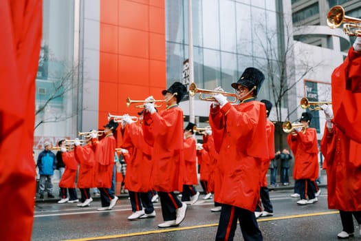 A vibrant parade scene with musicians dressed in red raincoats playing trumpets.
