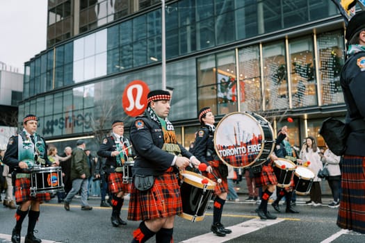 Participants in colorful kilts perform energetically in a joyful urban parade