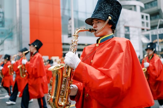 A lively marching band in colorful costumes performs for onlookers in the city