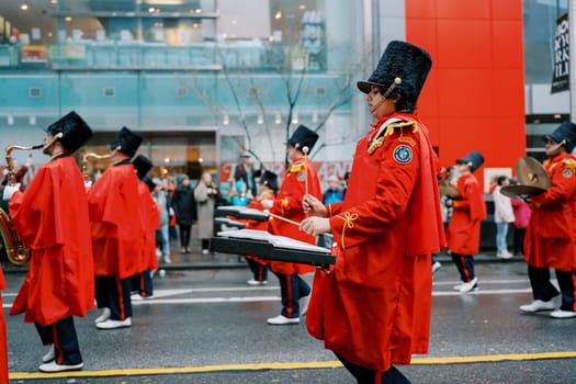 Exciting parade featuring musicians in vibrant red attire, lively atmosphere.