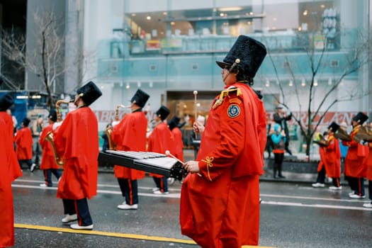 A parade featuring performers in bright red outfits and tall hats, creating enchantment