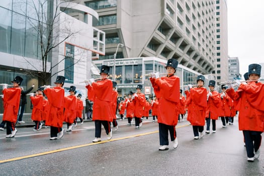 Joyful participants in vibrant red uniforms are marching through city streets