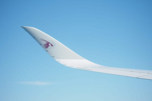 A close-up of an airplane wing gliding in the sky under sunlight.