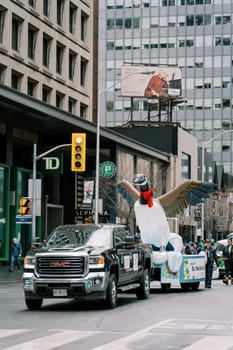 A vibrant parade float with a swan costume captured in a bustling city.