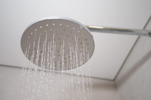 Water flows from a sleek shower head in a contemporary bathroom setting.