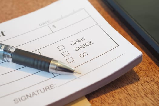 Close-up of a document showing payment method choices and a pen.