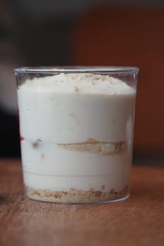 Layers of smooth cream and cake dessert in a transparent cup.