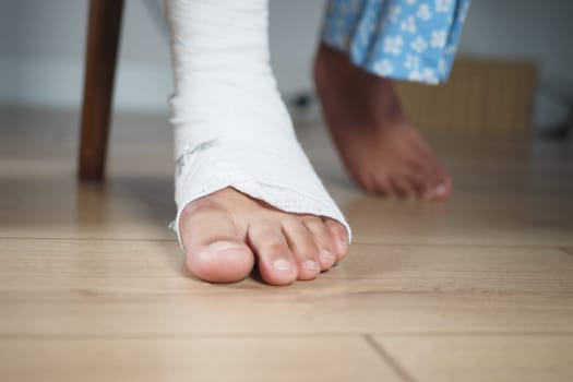 A bandaged foot hovers above a wooden floor, indicating healing progress.