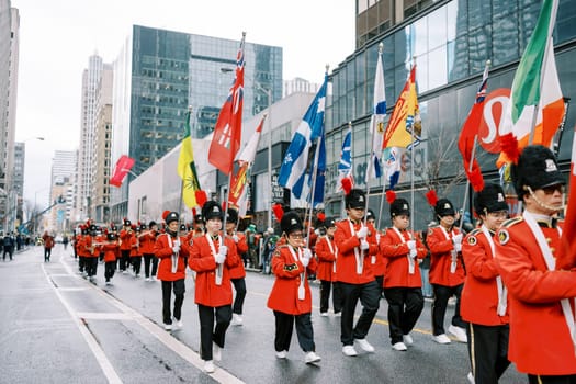 A vibrant parade featuring marching band in bright red uniforms, flags waving.