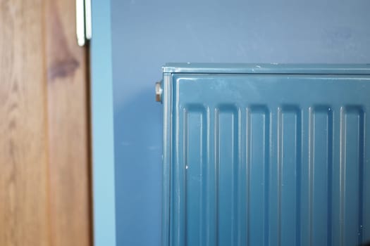A blue radiator is positioned alongside a wooden wall, adding depth.