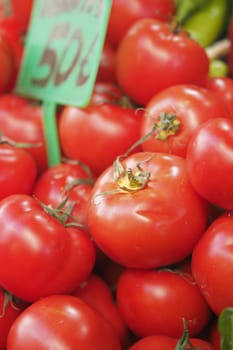 Bright red tomatoes displayed for sale at a market stall during the day.
