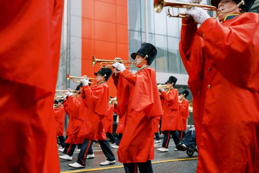 A cheerful marching band in bright red uniforms plays trumpets, creating joy