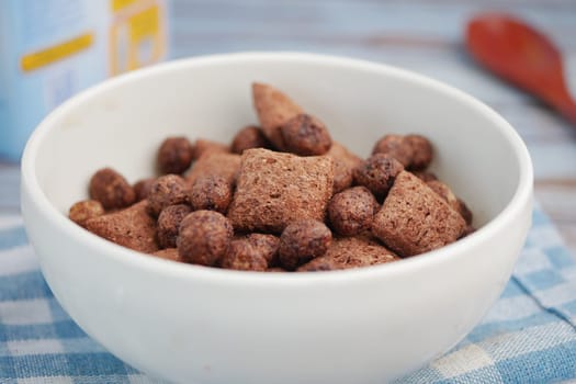 A bowl filled with different shapes and sizes of chocolate cereal.