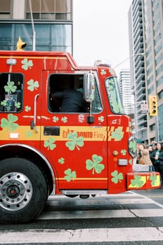 A vibrant and colorful fire truck adorned with shamrocks on bustling city streets
