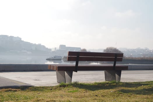 A bench sits quietly by the river, offering a peaceful view at dawn.