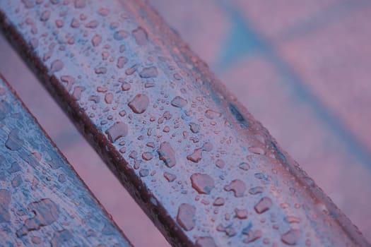 Water droplets collect on a wooden bench after a light rain shower.