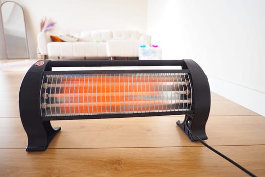A space heater emits warmth in a cozy, well-lit living area during winter.