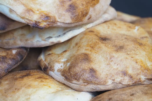 Freshly baked flatbreads piled high in a bustling market stall.