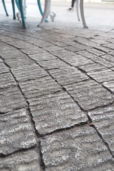 Close-up of patterned cobblestone surface with outdoor furniture nearby
