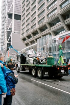 A colorful parade float with festive decorations moves down a busy street