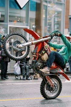 A skilled motorcyclist impressively showcases thrilling stunts on a busy city street