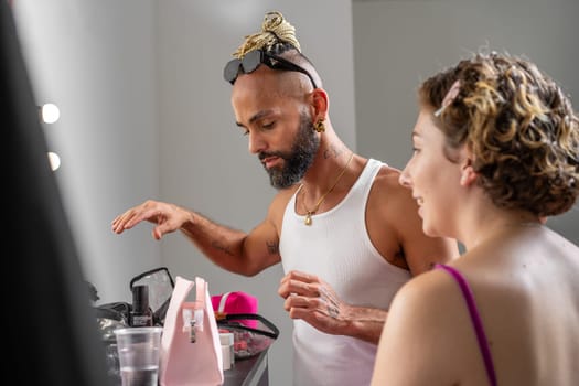 Professional male makeup artist applying makeup on female model in studio. Woman preparing for photoshoot, with makeup artist enhancing her look for the session