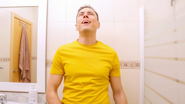 Adult man wearing yellow t shirt is peeing in his bathroom, feeling comfortable