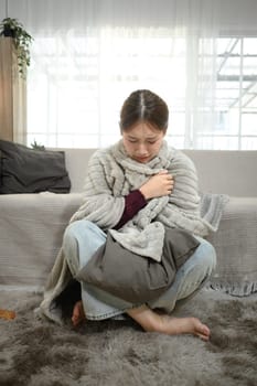 Sick woman wrapped in a blanket feeling unwell. Illness and home recovery concept.