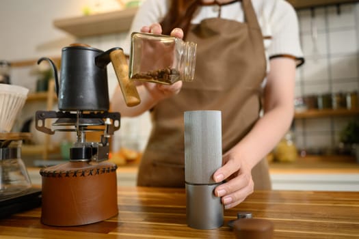 Young woman grinds coffee beans and sets up a brewing station in a modern kitchen.
