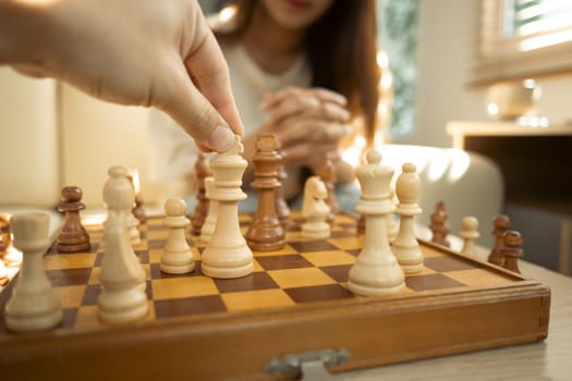 Close up of hand moves a chess piece on a classic wooden chessboard.