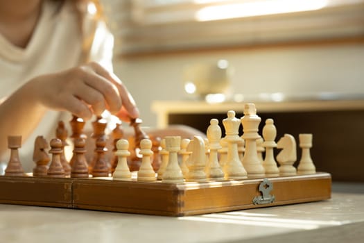 Hand holding chess piece, making a move on a classic wooden chessboard.