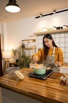 Happy asian woman in an apron stands in a kitchen, preparing a quick and easy meal.