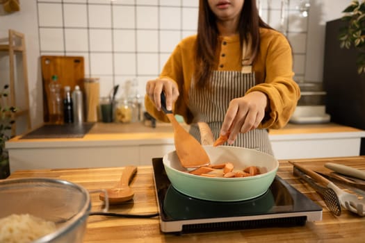Happy asian woman in apron preparing meal in a stylish home kitchen.