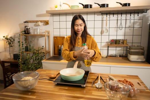 Happy asian woman in apron preparing meal in a stylish home kitchen.