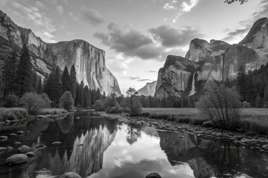The stunning landscape features towering mountains and a calm river, with trees lining the banks. The black and white image creates a tranquil atmosphere during twilight hours.