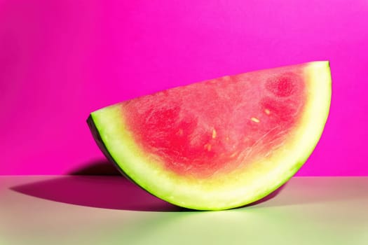A fresh slice of watermelon showcases its juicy pink flesh and green rind, positioned on a pastel surface. The playful pink backdrop adds a lively touch to this summery arrangement.