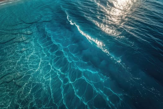 Sunlight reflects off the gently rippling water, illuminating a vivid expanse of turquoise blue. Waves create intricate patterns as they ebb and flow, creating a tranquil atmosphere by the shore.