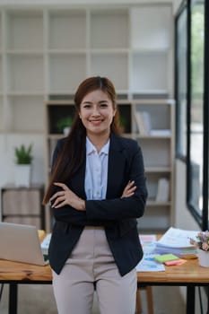 Confident business woman smiling Show successful gestures at her desk with market charts and documents in office.