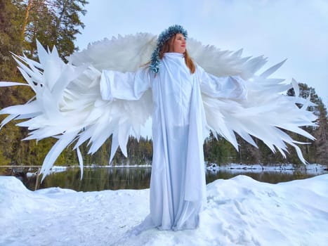 A group of girls dressed in white dresses role-play by a snow-covered lake, embodying a fairy tale winter scene amidst nature's serene beauty.