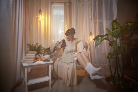 A middle-aged woman relaxes in a cozy apartment, seated comfortably with her dog, enjoying a peaceful evening filled with comfort.