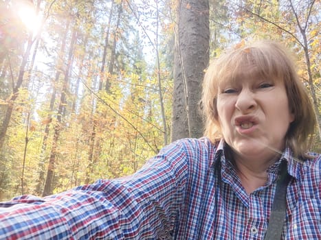 A blonde, middle-aged woman shows her playful side, making funny faces during a fun forest trip.